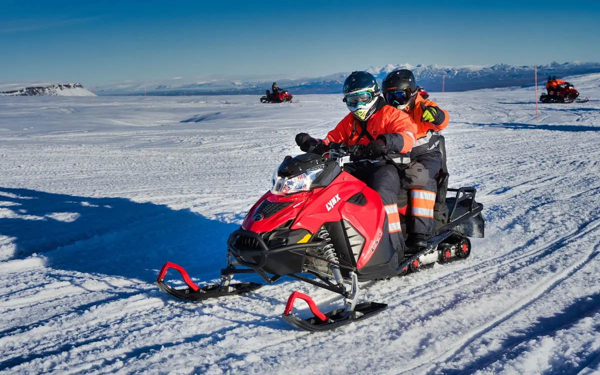 Ein Fahrer mit Helm und Thermoanzug auf einem Schneemobil auf einer isländischen Eiskappe